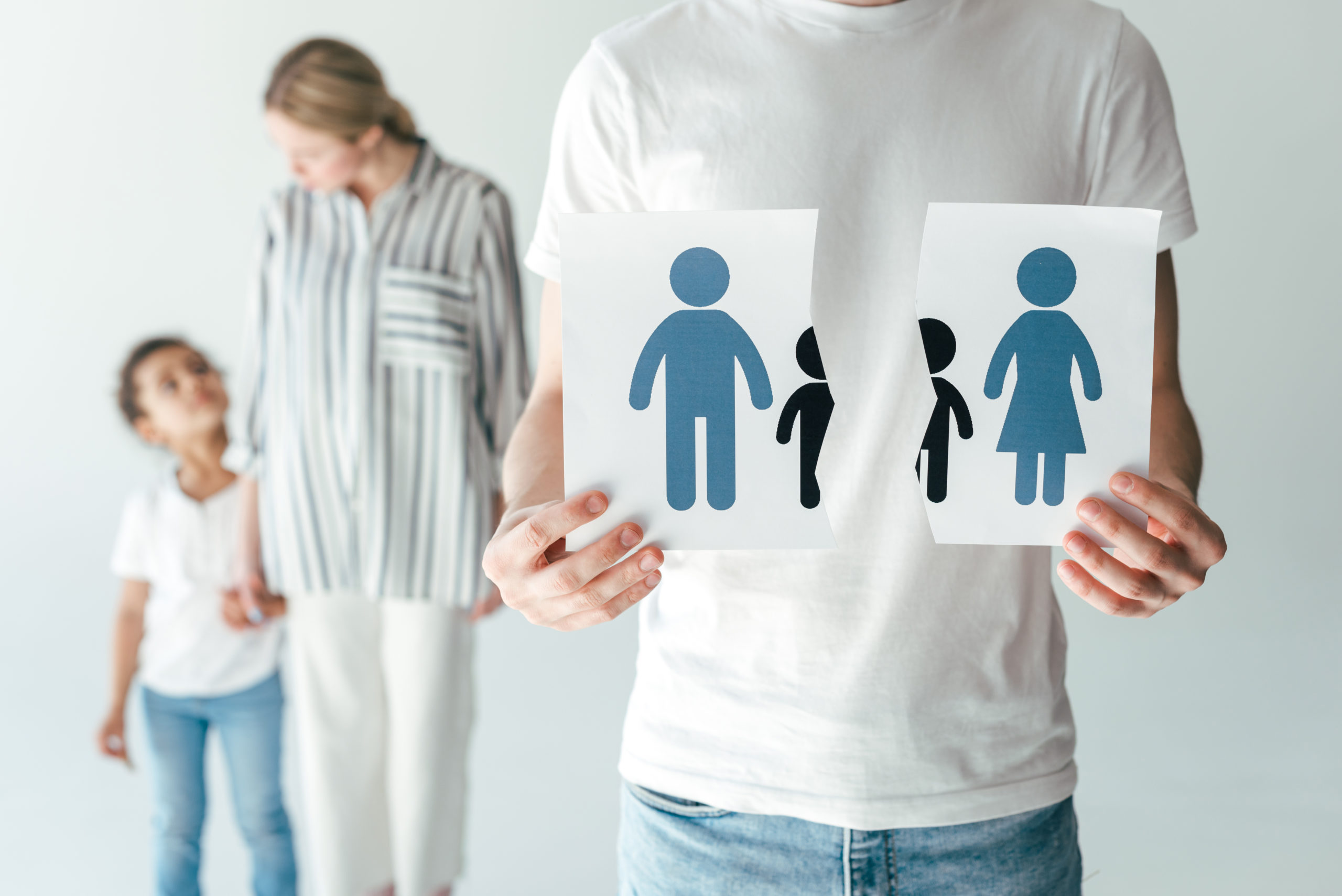 manos partiendo papel con una familia y familia de fondo